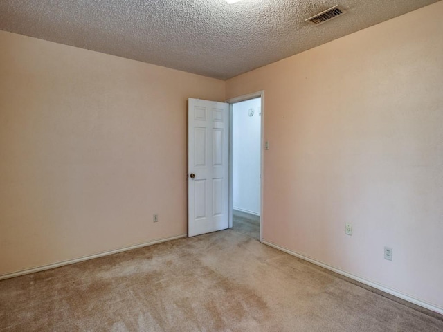 spare room with a textured ceiling and light colored carpet