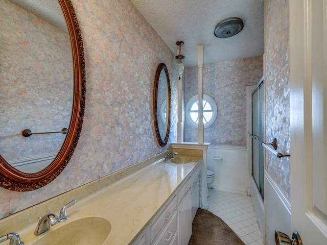 full bathroom featuring vanity, shower / bath combination with glass door, tile patterned floors, toilet, and a textured ceiling