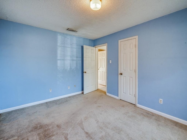 spare room with a textured ceiling and light carpet