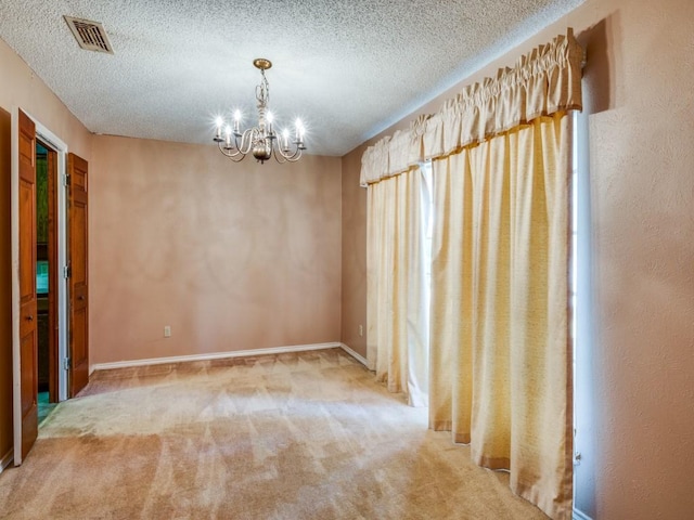 carpeted spare room with a textured ceiling and a chandelier