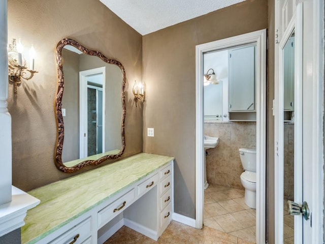 bathroom with tile patterned flooring, toilet, tile walls, and a textured ceiling