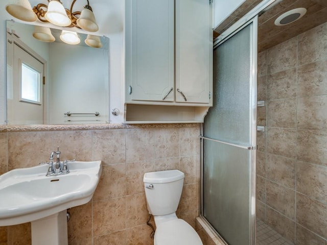 bathroom featuring an enclosed shower, toilet, sink, and tile walls