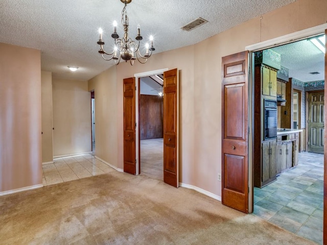 hallway with light carpet, a textured ceiling, and a chandelier