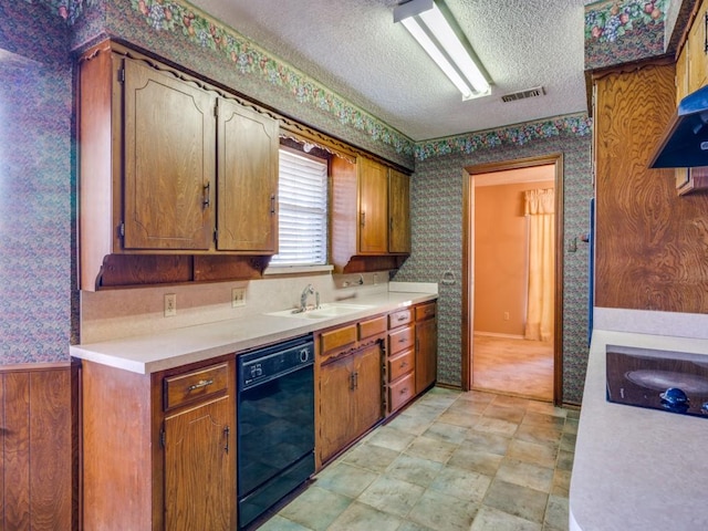 kitchen featuring wood walls, sink, a textured ceiling, and black dishwasher