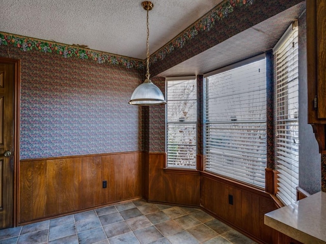 unfurnished dining area with a textured ceiling and wooden walls