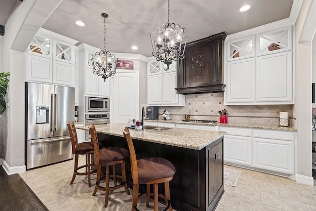 kitchen featuring decorative light fixtures, white cabinetry, stainless steel appliances, and a kitchen island with sink