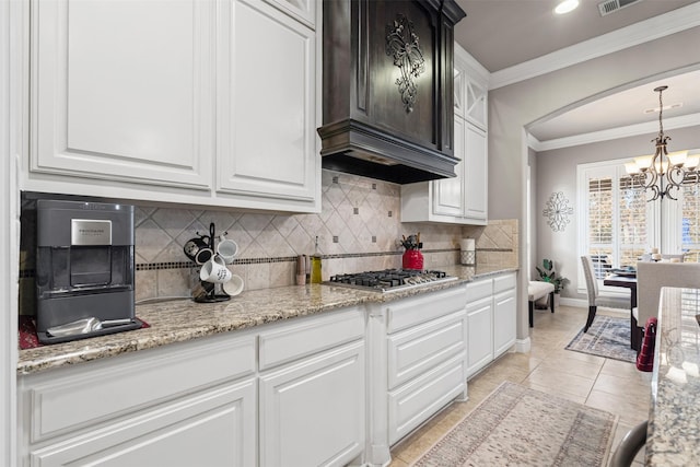 kitchen featuring white cabinets, an inviting chandelier, stainless steel gas cooktop, and crown molding