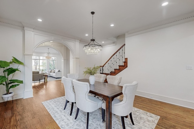 dining room featuring hardwood / wood-style floors, decorative columns, and an inviting chandelier