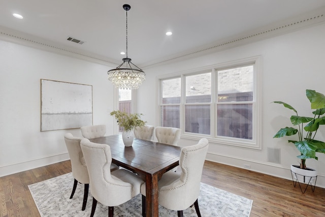 dining room with hardwood / wood-style floors, a notable chandelier, and crown molding