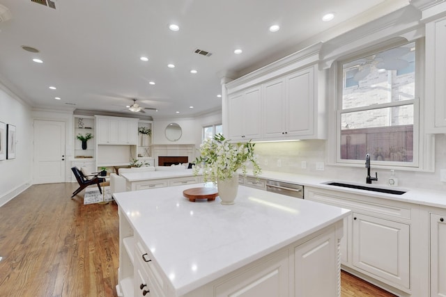 kitchen with ceiling fan, sink, a kitchen island, light hardwood / wood-style flooring, and white cabinets