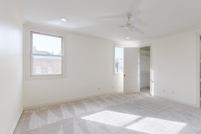 spare room featuring light carpet, a wealth of natural light, crown molding, and ceiling fan