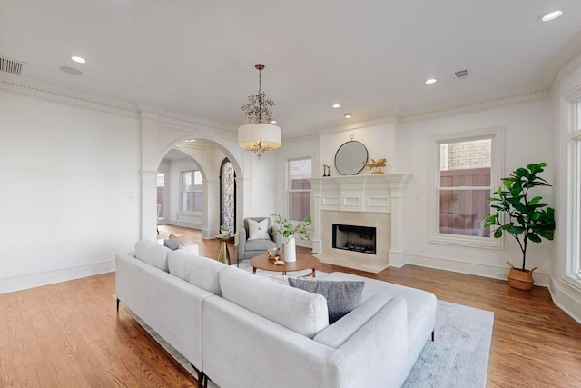 living room with crown molding, a high end fireplace, and light hardwood / wood-style floors