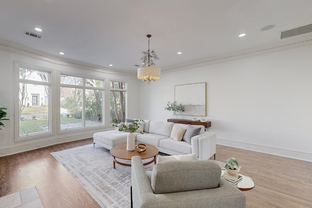 living room with hardwood / wood-style floors, ornamental molding, and a notable chandelier