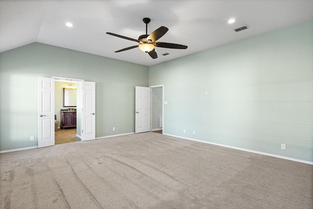 unfurnished bedroom featuring connected bathroom, ceiling fan, light colored carpet, and vaulted ceiling