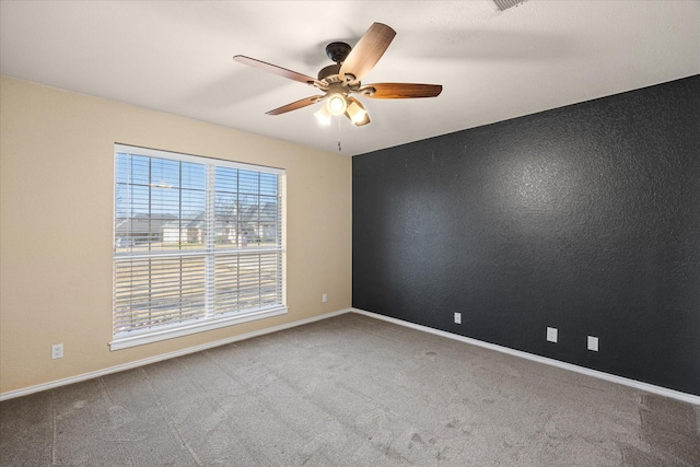 carpeted empty room with a ceiling fan and baseboards