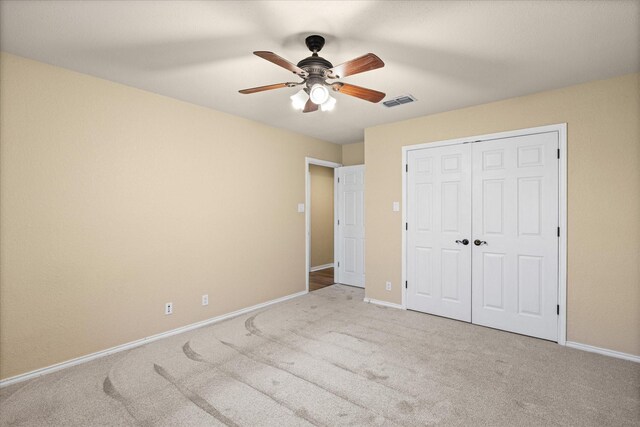 unfurnished bedroom with a closet, light colored carpet, and ceiling fan