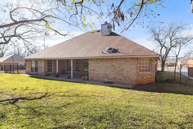 rear view of property featuring a yard, fence, a chimney, and a patio