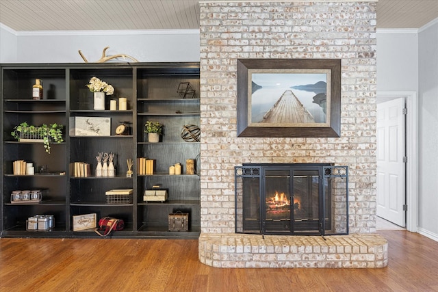 living room with hardwood / wood-style floors, ornamental molding, and a brick fireplace