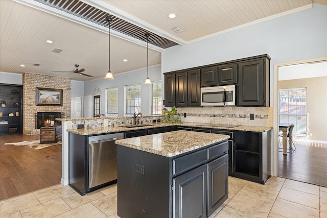 kitchen with appliances with stainless steel finishes, open floor plan, a kitchen island, and hanging light fixtures