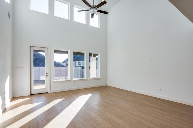 unfurnished living room featuring a high ceiling, a wealth of natural light, and light hardwood / wood-style flooring