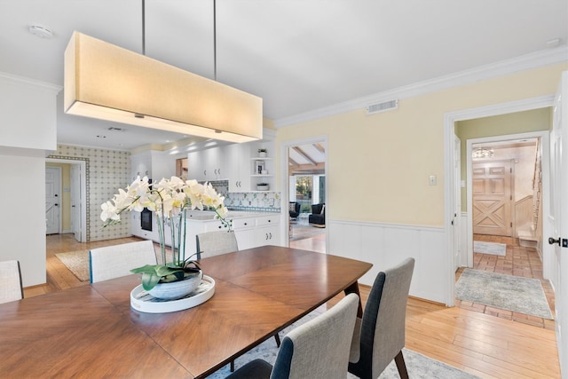 dining room featuring light wood-type flooring and crown molding