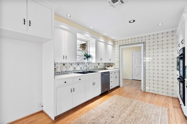 kitchen with white cabinets, dishwasher, sink, and light hardwood / wood-style flooring