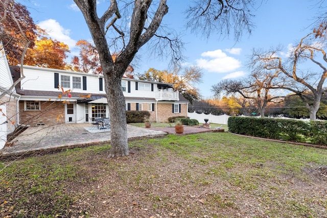 rear view of property with a yard, a balcony, and a patio area