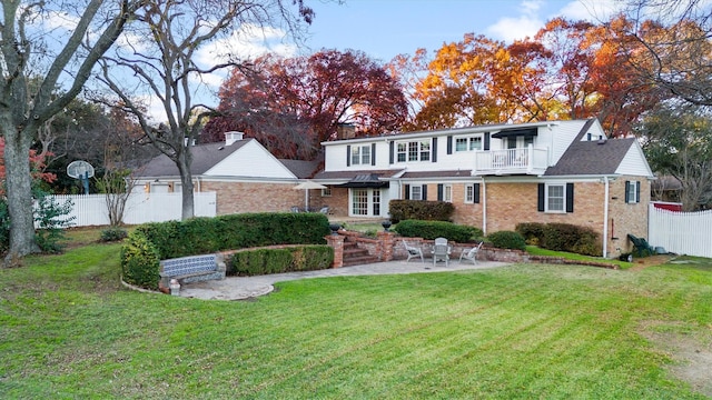 view of property with a balcony, a patio, and a front yard