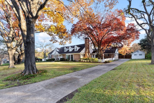 cape cod home featuring an outbuilding and a front yard