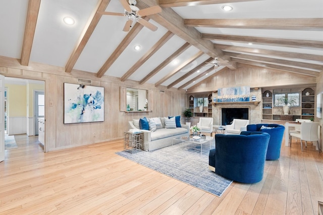 living room with ceiling fan, wooden walls, lofted ceiling with beams, and light hardwood / wood-style floors