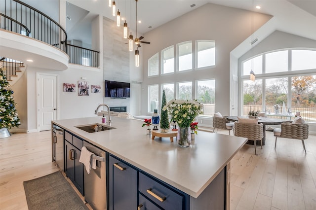 kitchen with sink, light wood-type flooring, an island with sink, and blue cabinets