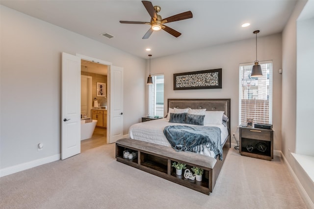 carpeted bedroom featuring multiple windows, ensuite bathroom, and ceiling fan