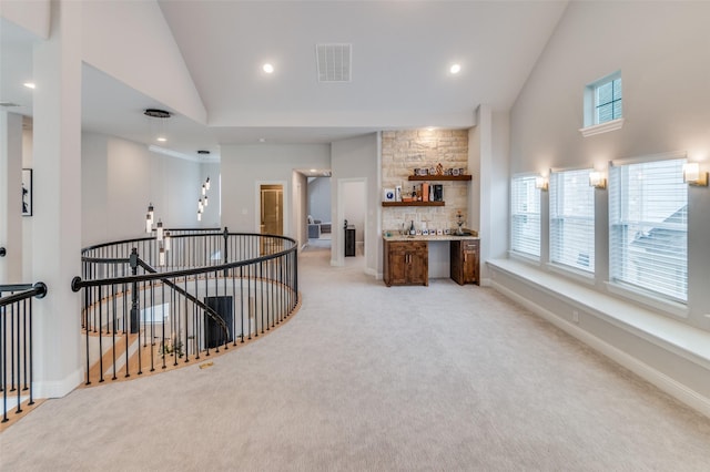 corridor featuring light carpet and high vaulted ceiling