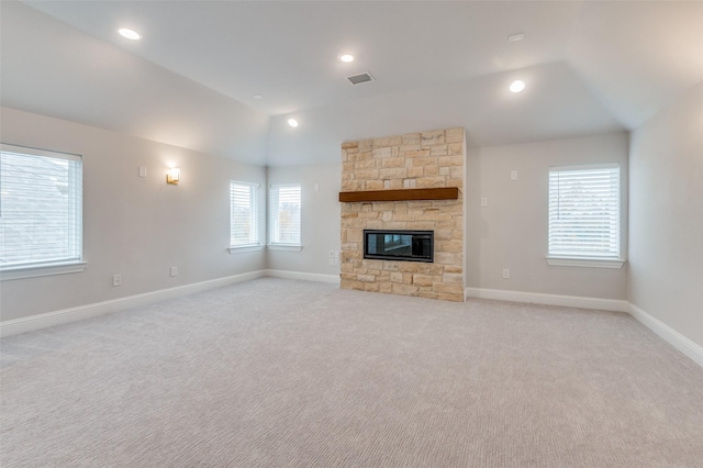 unfurnished living room with a fireplace, vaulted ceiling, and light carpet