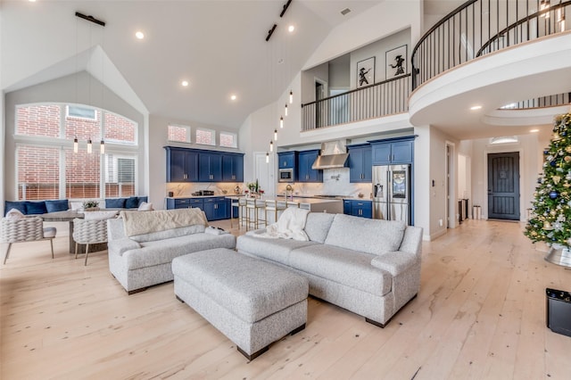 living room featuring a towering ceiling, sink, and light hardwood / wood-style floors