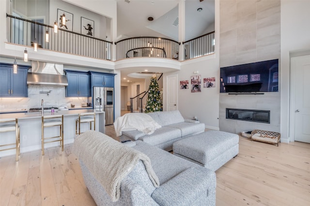 living room featuring a towering ceiling, a fireplace, and light hardwood / wood-style flooring