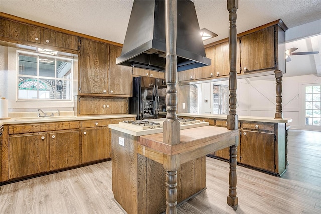 kitchen featuring black fridge with ice dispenser, sink, island range hood, a center island, and light wood-type flooring