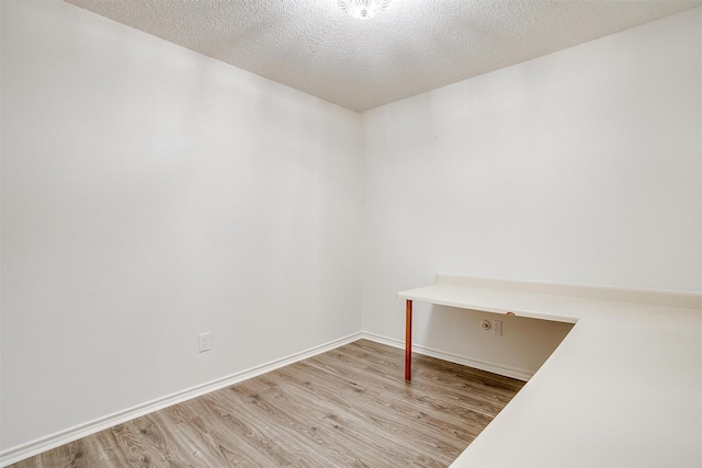 spare room with a textured ceiling and light wood-type flooring