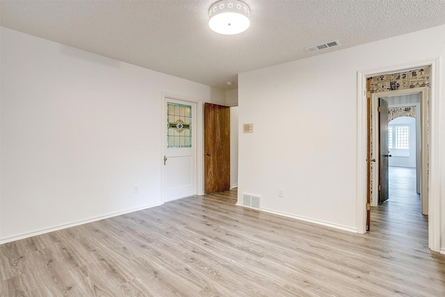 empty room featuring a textured ceiling and light wood-type flooring