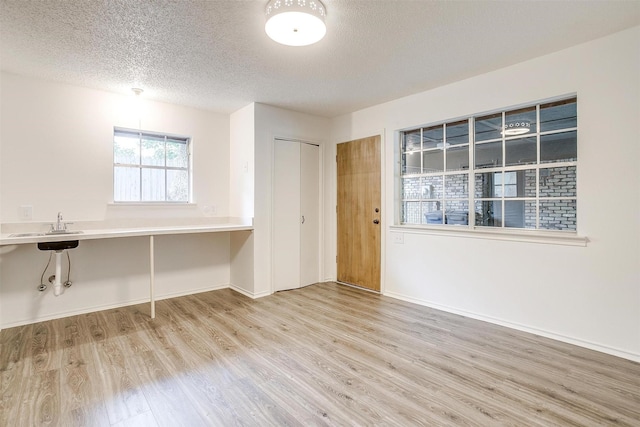 empty room with a textured ceiling and light hardwood / wood-style flooring