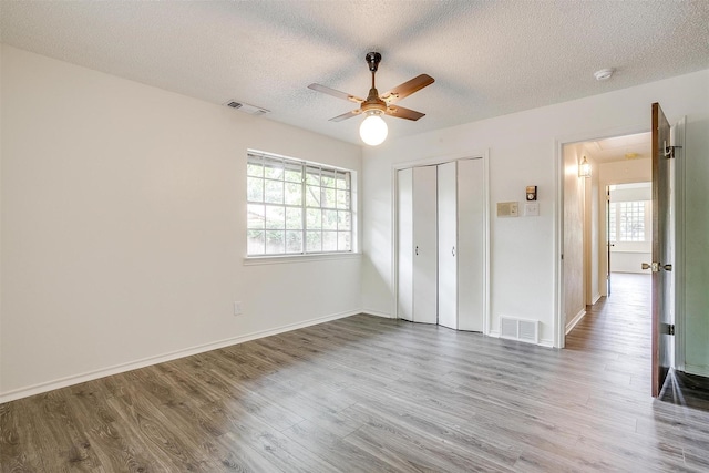 unfurnished bedroom with ceiling fan, a closet, light hardwood / wood-style flooring, and a textured ceiling