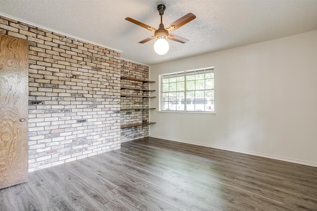 unfurnished living room with ceiling fan, brick wall, a textured ceiling, and dark hardwood / wood-style flooring