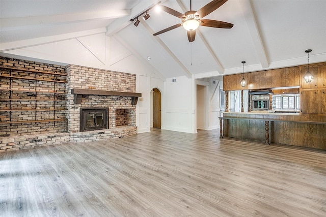 unfurnished living room featuring ceiling fan, beam ceiling, high vaulted ceiling, a fireplace, and wood-type flooring