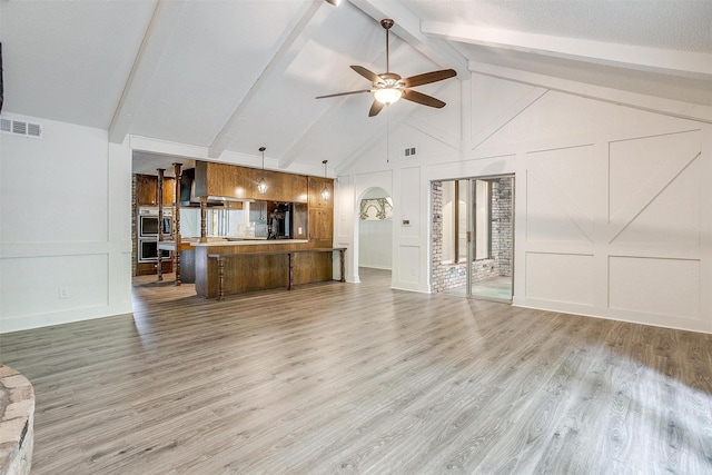 unfurnished living room with ceiling fan, high vaulted ceiling, light wood-type flooring, and beam ceiling