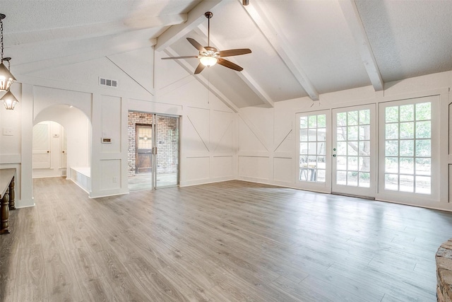 unfurnished living room with lofted ceiling with beams, ceiling fan, a textured ceiling, and light wood-type flooring