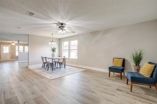 dining area featuring a textured ceiling, light hardwood / wood-style flooring, and a notable chandelier