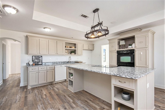 kitchen featuring pendant lighting, dark wood-type flooring, a center island, light stone counters, and black appliances