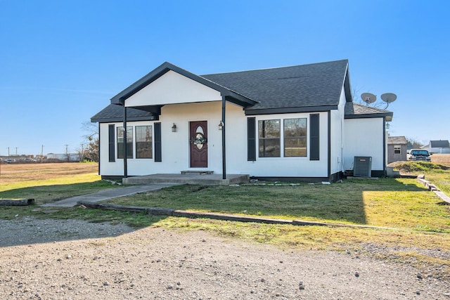 view of front of property with central AC unit, a front lawn, and roof with shingles