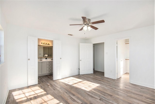 unfurnished bedroom with sink, a spacious closet, wood-type flooring, and ensuite bathroom