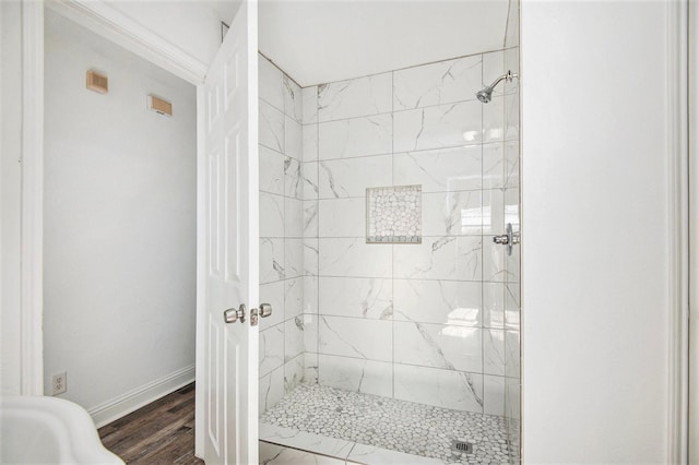 bathroom with tiled shower and hardwood / wood-style floors